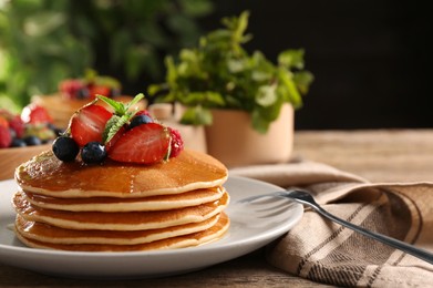 Photo of Tasty pancakes with fresh berries and mint on wooden table, closeup. Space for text