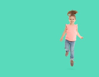 Cute girl jumping on turquoise background, space for text