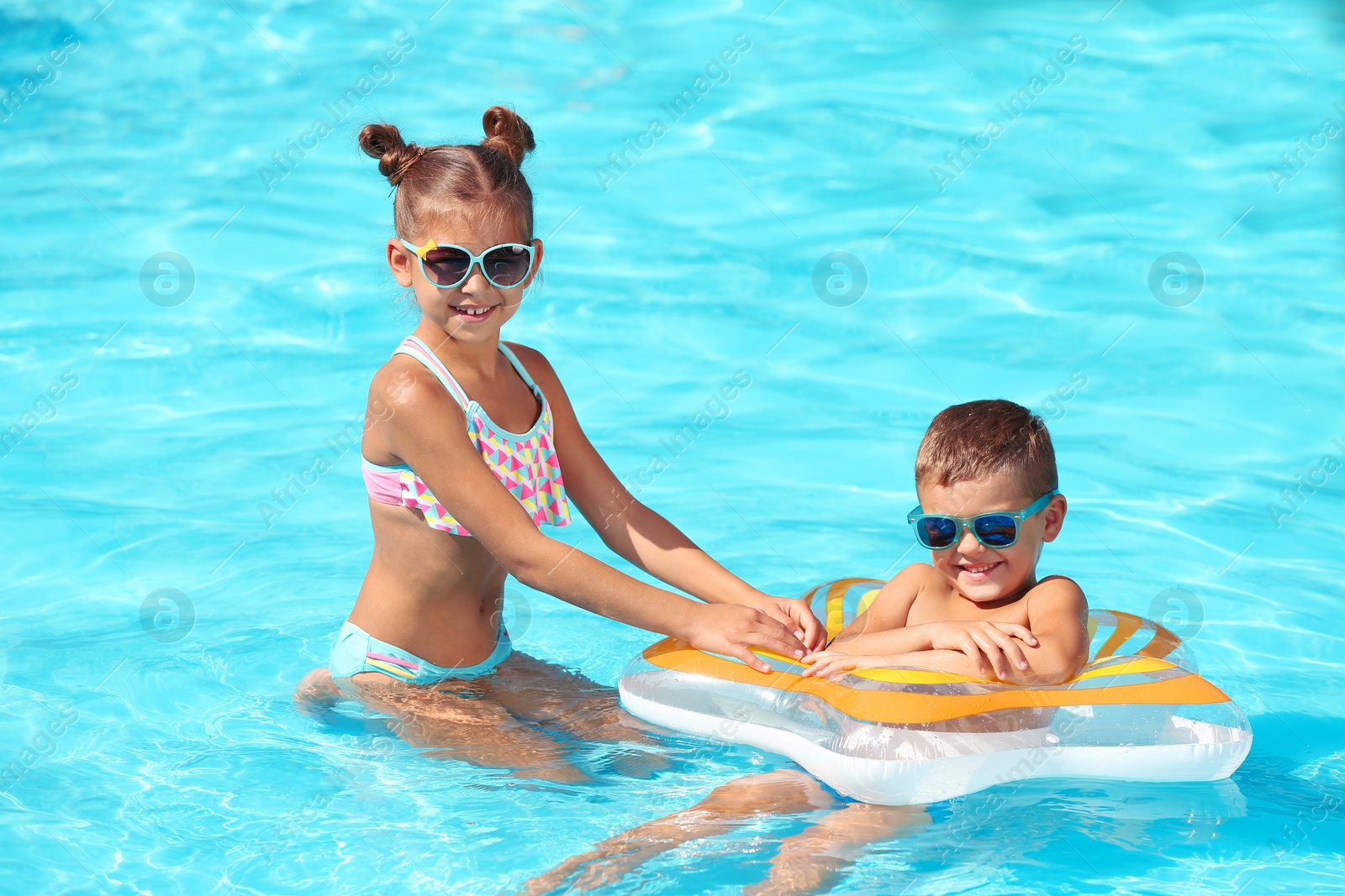 Photo of Cute little children with inflatable ring in swimming pool