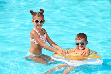 Photo of Cute little children with inflatable ring in swimming pool