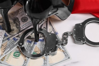 Photo of Prostitution concept. High heeled shoes, handcuffs and dollar banknotes on white marble background, closeup