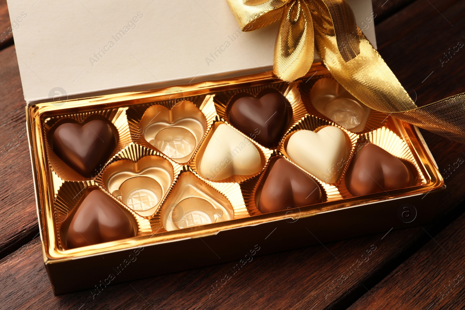 Photo of Partially empty box of chocolate candies on wooden table