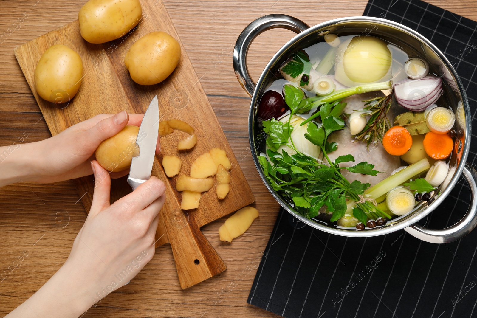 Photo of Woman peeling potato for cooking tasty bouillon at wooden table, top view