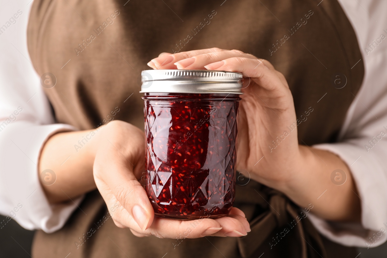 Photo of Woman with jar of raspberry jam, closeup