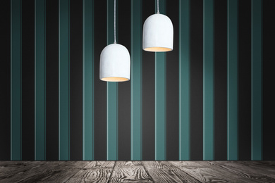 Stylish pendant lamps hanging near striped wall in room