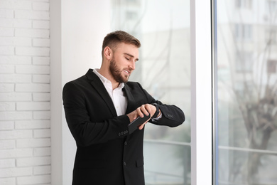 Young businessman checking time near window at home