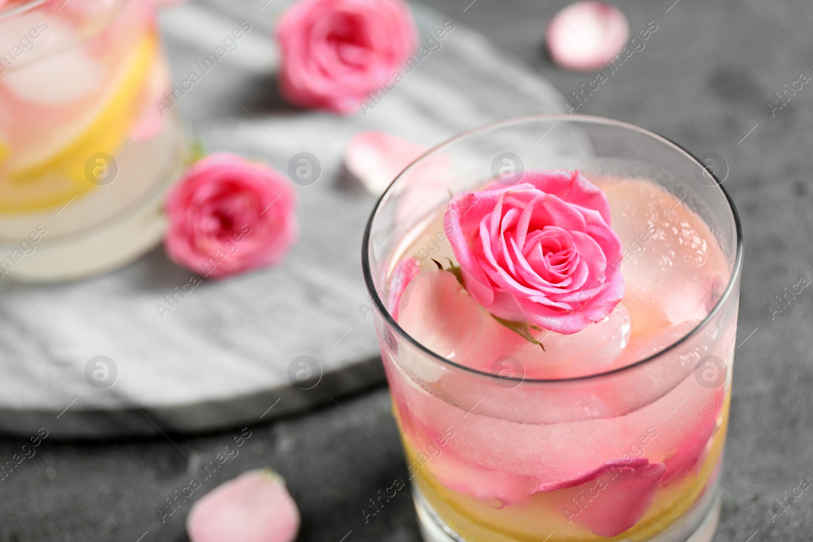 Photo of Delicious refreshing drink with lemon and rose on grey table, closeup