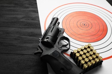 Photo of Shooting target, handgun and bullets on black wooden table, space for text