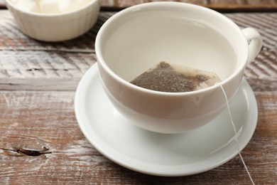 Tea bag in cup with hot water on wooden rustic table, closeup