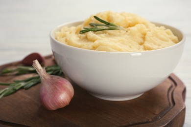 Photo of Bowl with mashed potatoes on wooden board