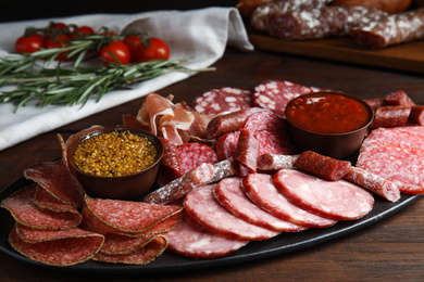 Photo of Different types of sausages with sauce served on wooden table