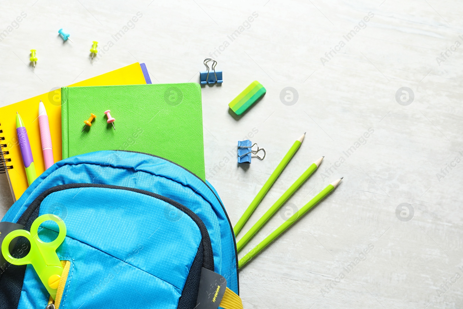 Photo of Flat lay composition with backpack, school stationery and space for text on light background