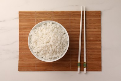 Photo of Bowl with delicious rice and chopsticks on white marble table, top view