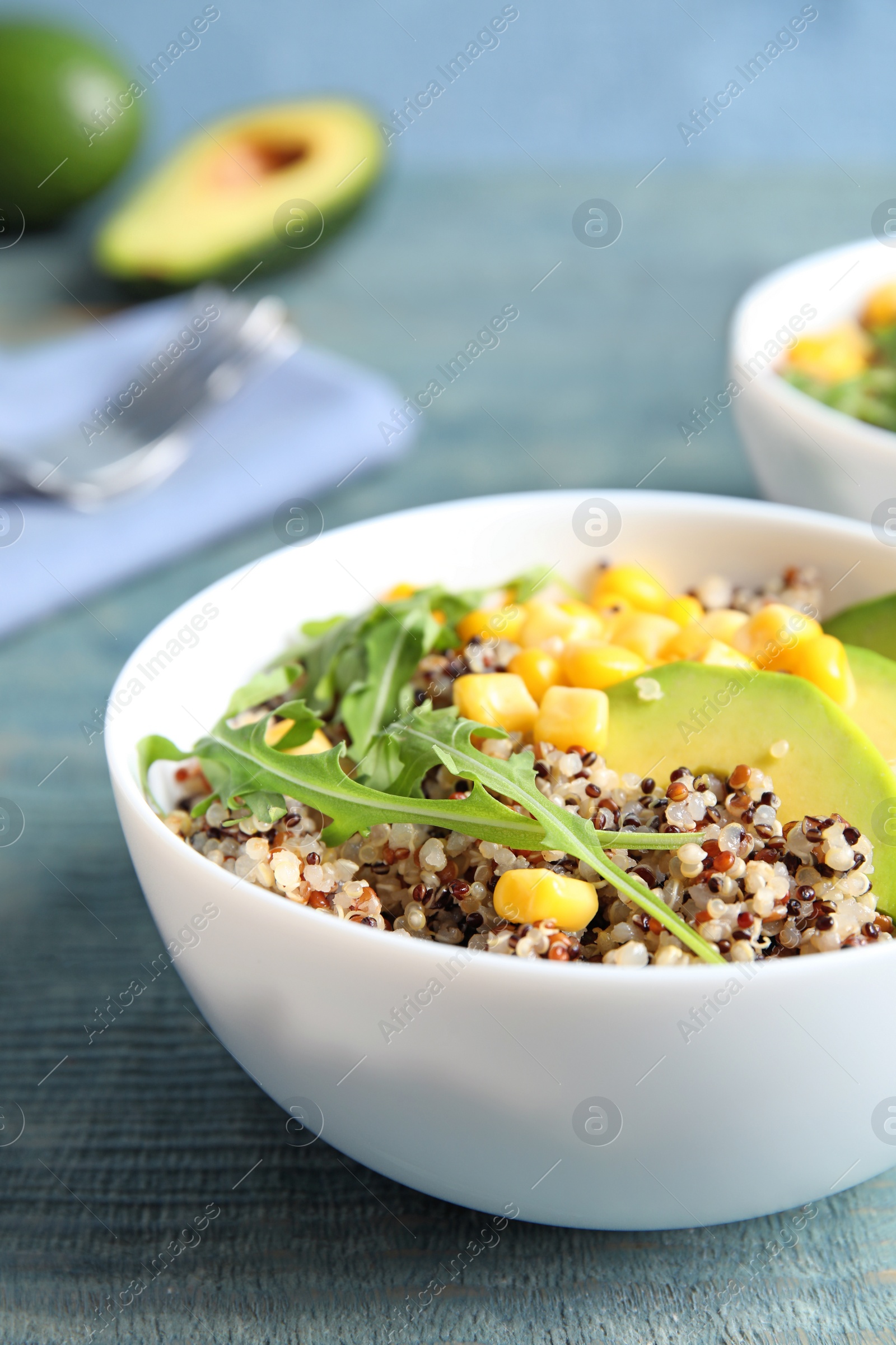 Photo of Healthy quinoa salad with vegetables in bowl on wooden table. Space for text