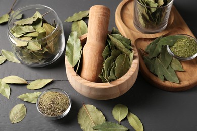 Photo of Whole and ground bay leaves on grey wooden table