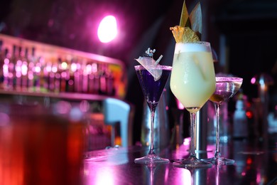 Photo of Different fresh alcoholic cocktails on counter in bar. Space for text