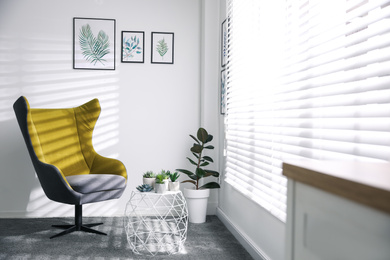 Comfortable armchair near white wall in light room