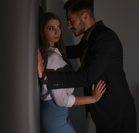 Photo of Boss molesting his female secretary on dark background. Sexual harassment at work
