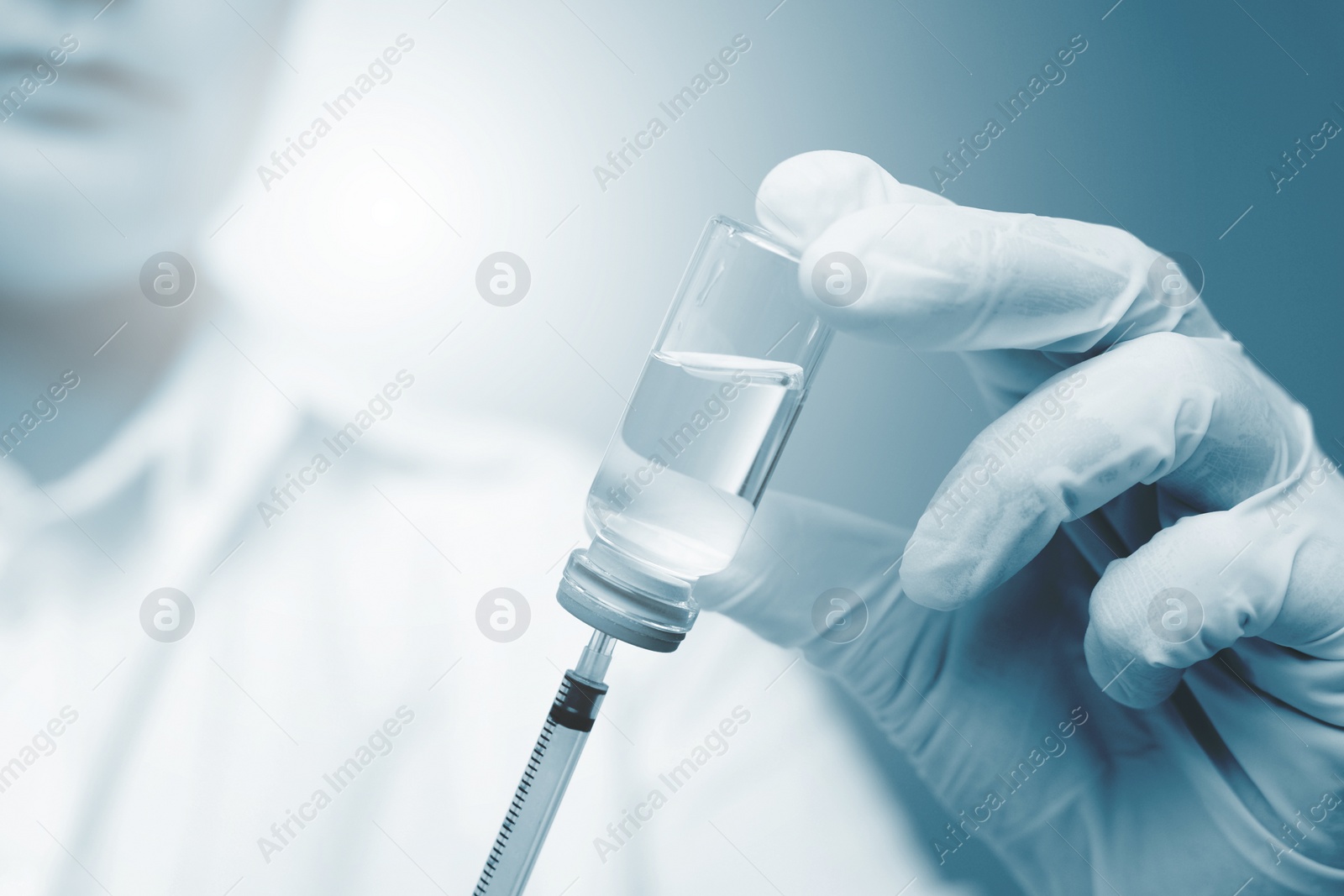 Image of Doctor filling syringe with medication from glass vial on background, selective focus. Color toned