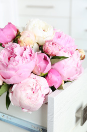 Photo of Bouquet of beautiful peonies in commode drawer indoors