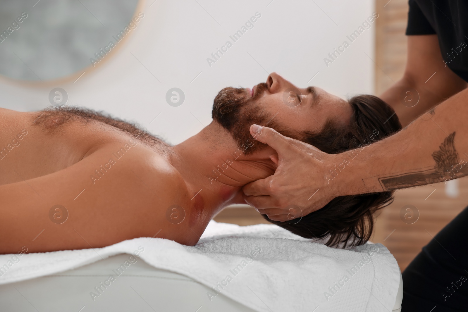 Photo of Man receiving professional neck massage in spa salon