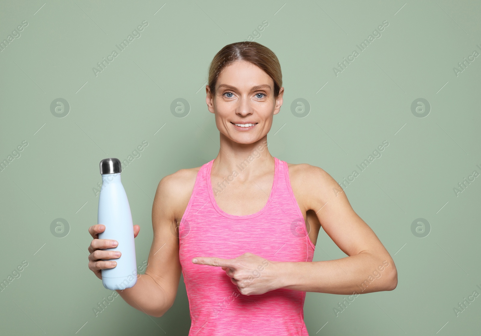 Photo of Sportswoman with thermo bottle on green background