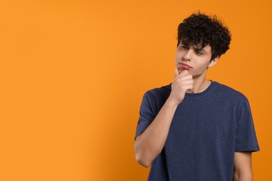 Photo of Portrait of thoughtful young man on orange background. Space for text