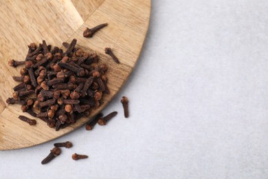 Pile of aromatic cloves on light table, top view. Space for text