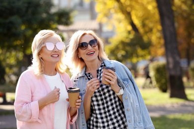 Photo of Happy mature women with coffee in park on sunny day