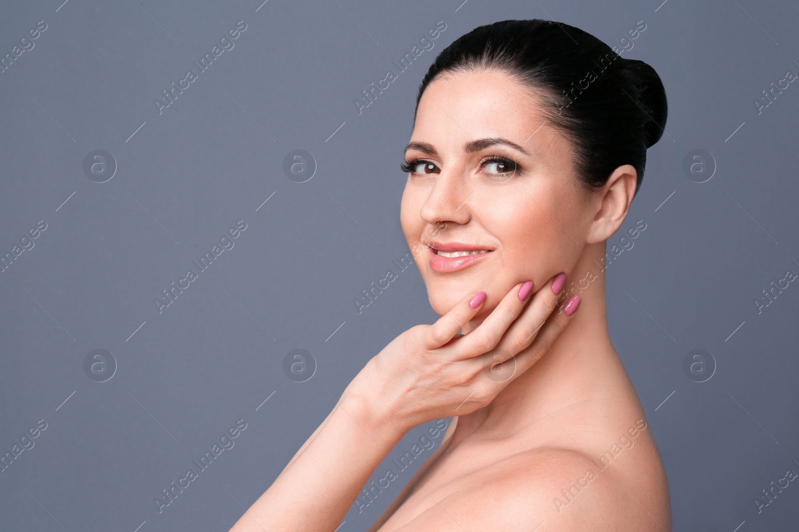 Photo of Beautiful woman with clean skin touching her face on grey background