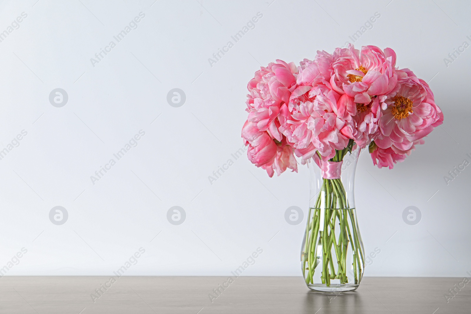 Photo of Beautiful bouquet of pink peonies in vase on table against white background. Space for text