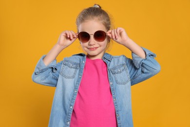 Photo of Girl in stylish sunglasses on orange background