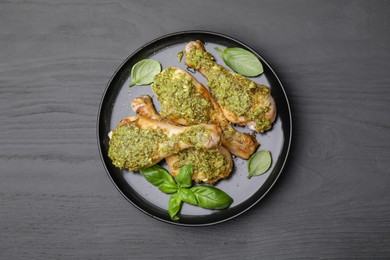 Delicious fried chicken drumsticks with pesto sauce and basil on gray wooden table, top view