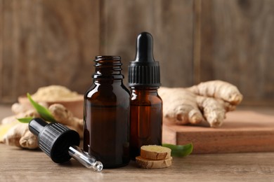 Photo of Ginger essential oil in bottles on wooden table