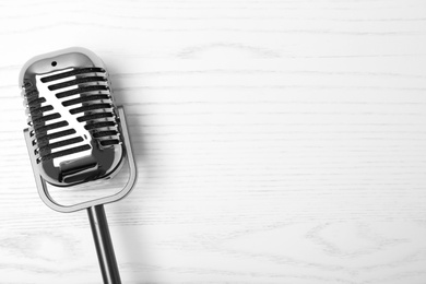 Photo of Retro microphone on wooden background, top view with space for text