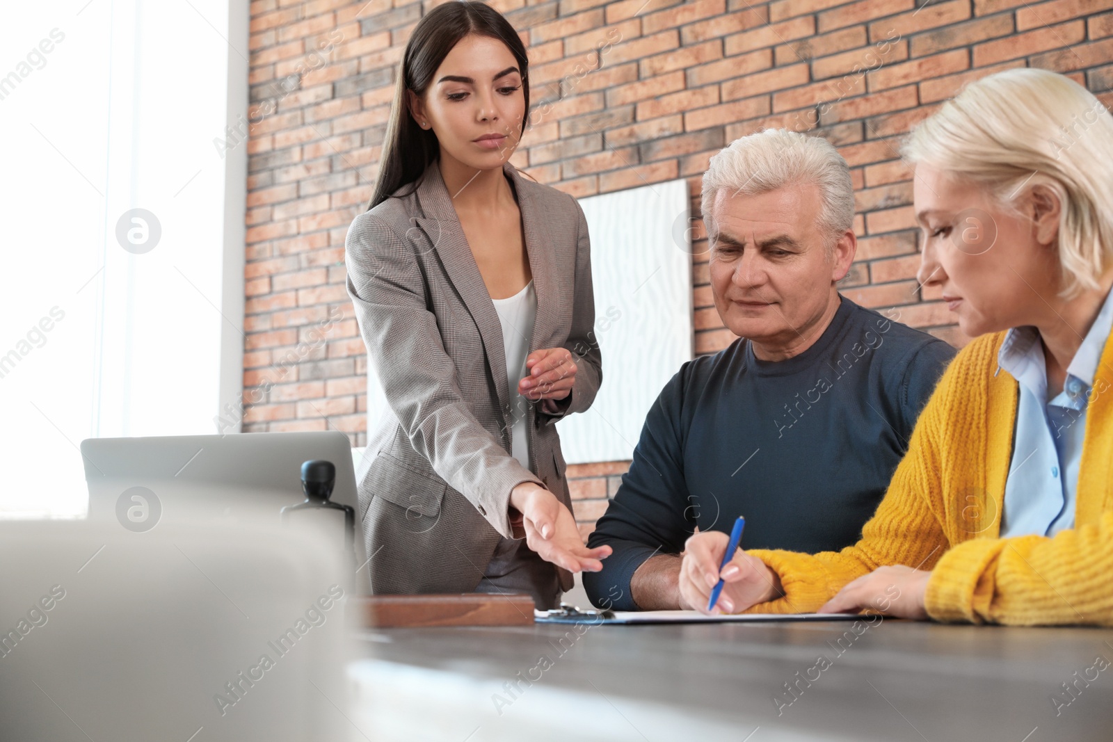 Photo of Female notary working with mature couple in office