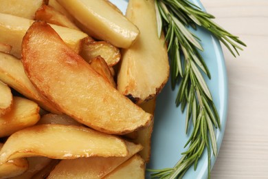 Photo of Plate with delicious baked potatoes and rosemary on white wooden table, closeup