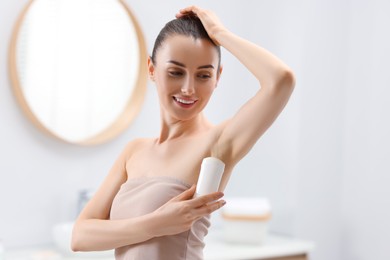 Photo of Beautiful young woman applying deodorant in bathroom