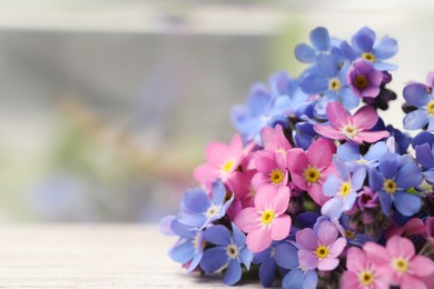 Photo of Beautiful blue and pink Forget-me-not flowers on white table. Space for text