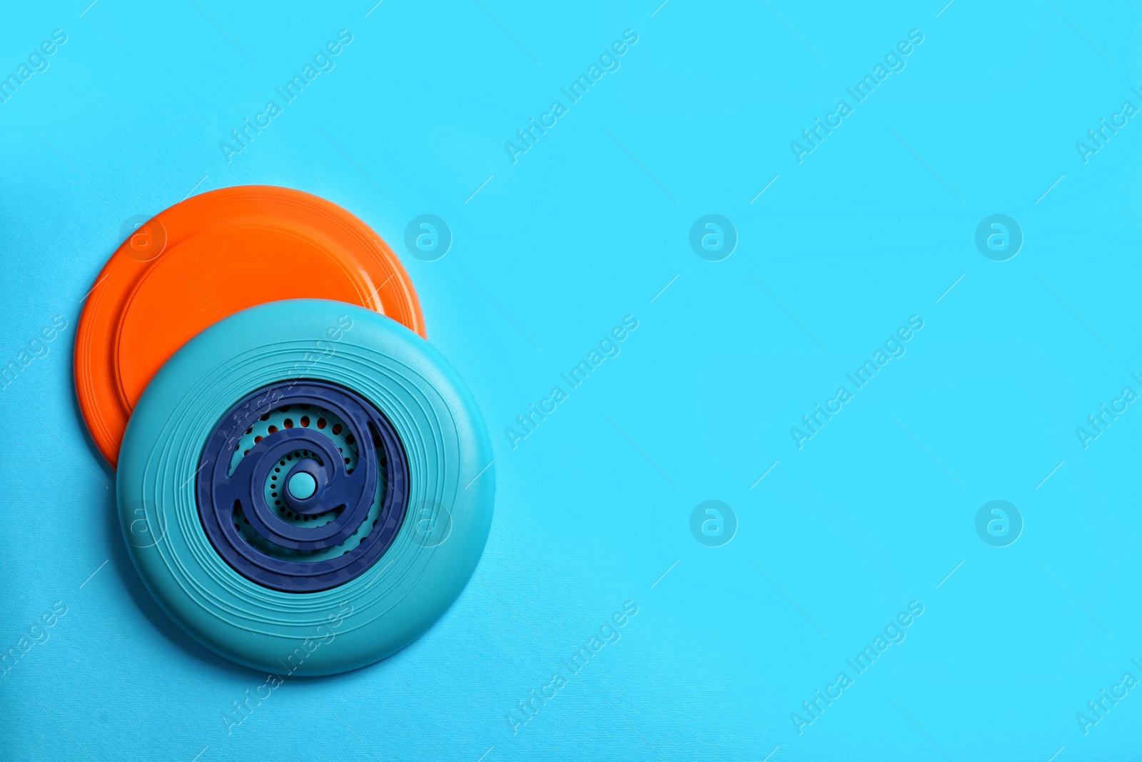 Photo of Plastic frisbee disks on light blue background, flat lay. Space for text