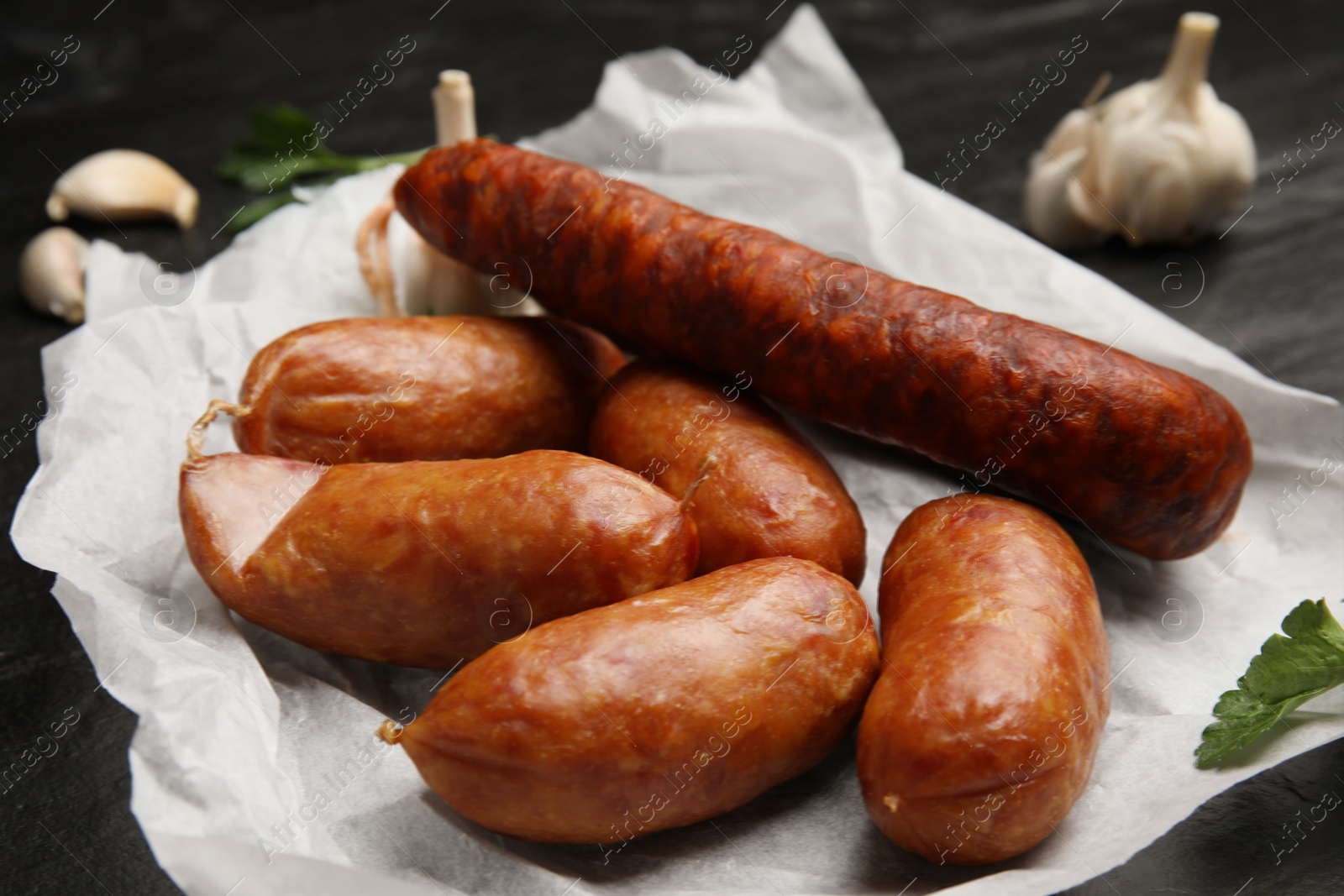 Photo of Delicious smoked sausages on parchment paper, closeup