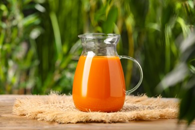 Photo of Tasty carrot juice on wooden table outdoors
