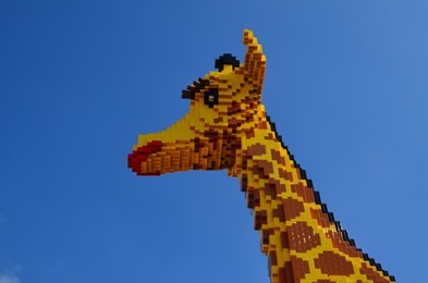 Photo of AMSTERDAM, NETHERLANDS - SEPTEMBER 10, 2022: Giraffe figure made with colorful Lego constructor against blue sky, low angle view