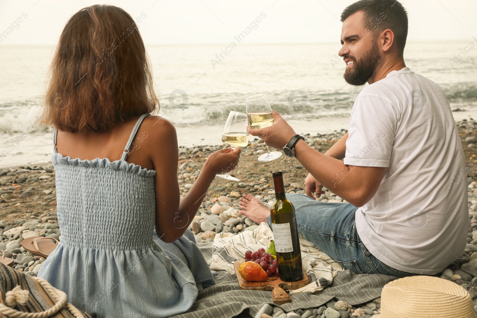 Photo of Young couple having picnic on beach near sea