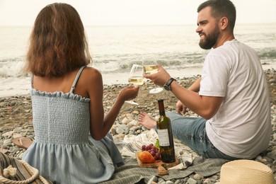 Photo of Young couple having picnic on beach near sea