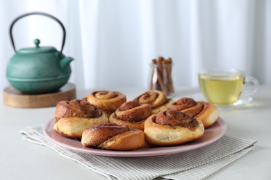 Many tasty cinnamon rolls on white table, space for text