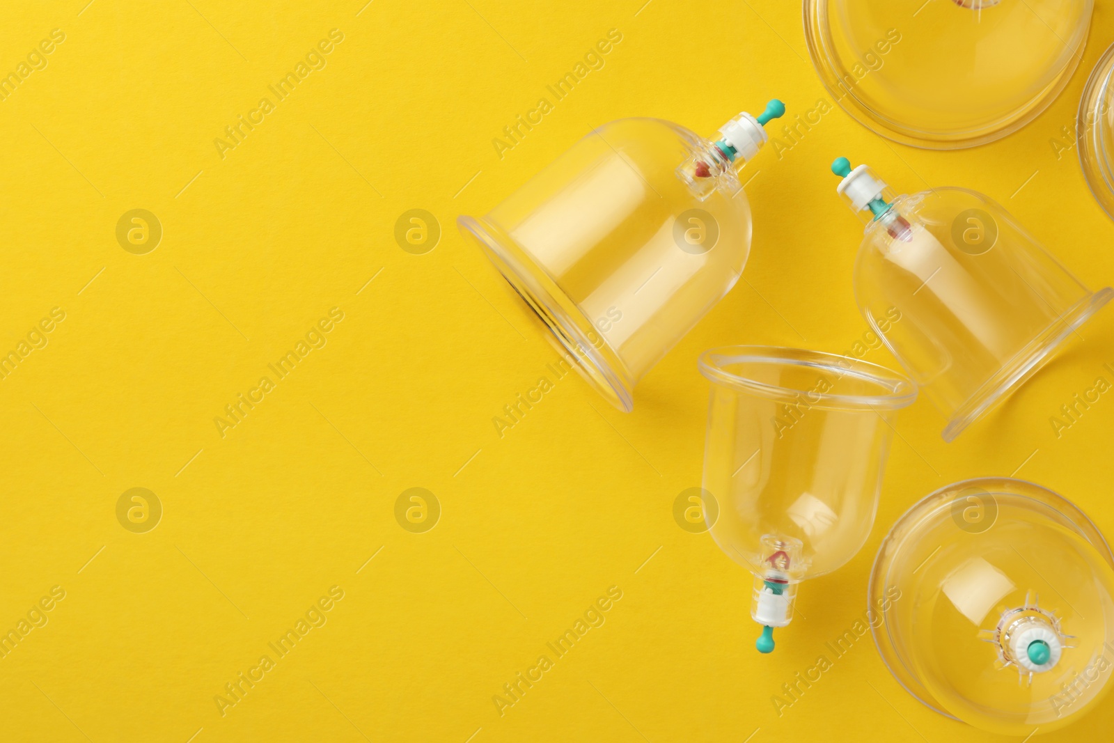 Photo of Plastic cups on yellow background, flat lay with space for text. Cupping therapy