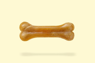 Image of Bone dog treat in air on beige background