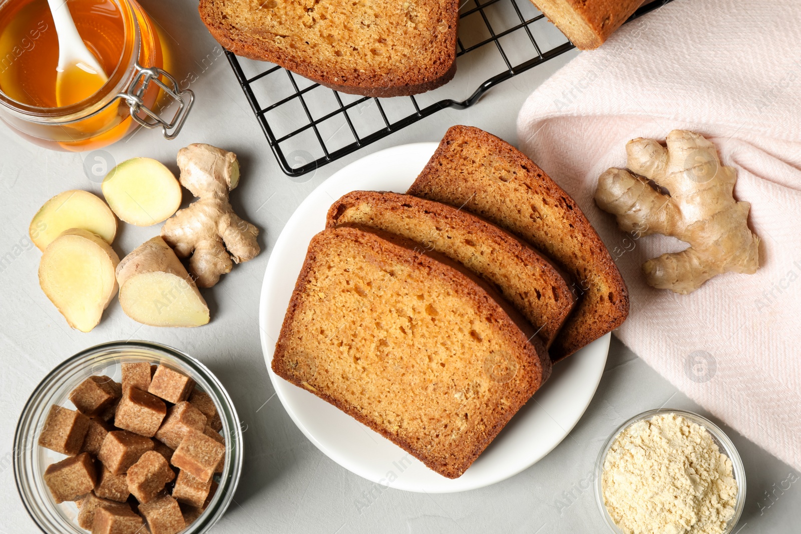 Photo of Fresh gingerbread cake slices and ingredients on light table, flat lay