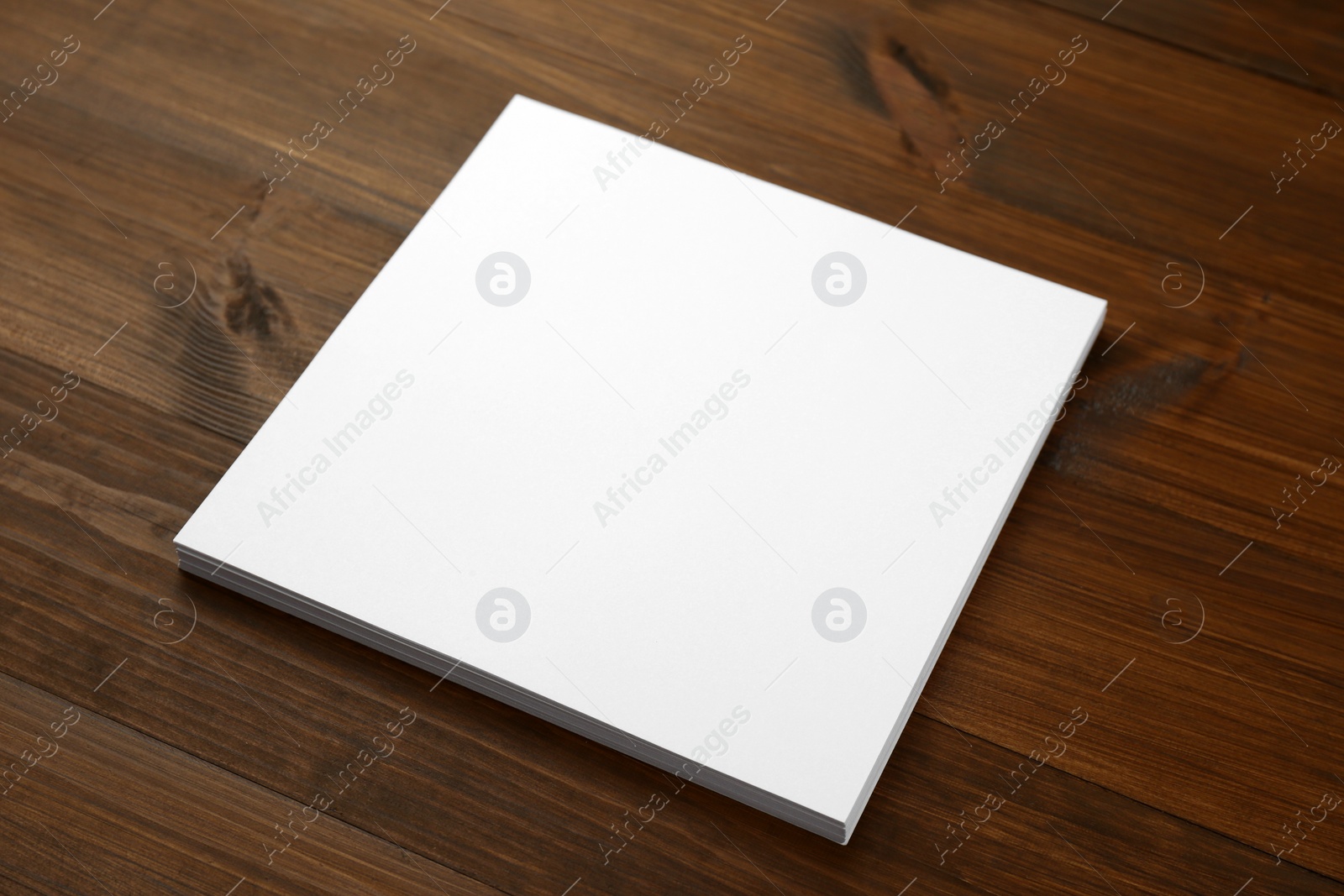 Photo of Stack of blank paper sheets on wooden table. Brochure design